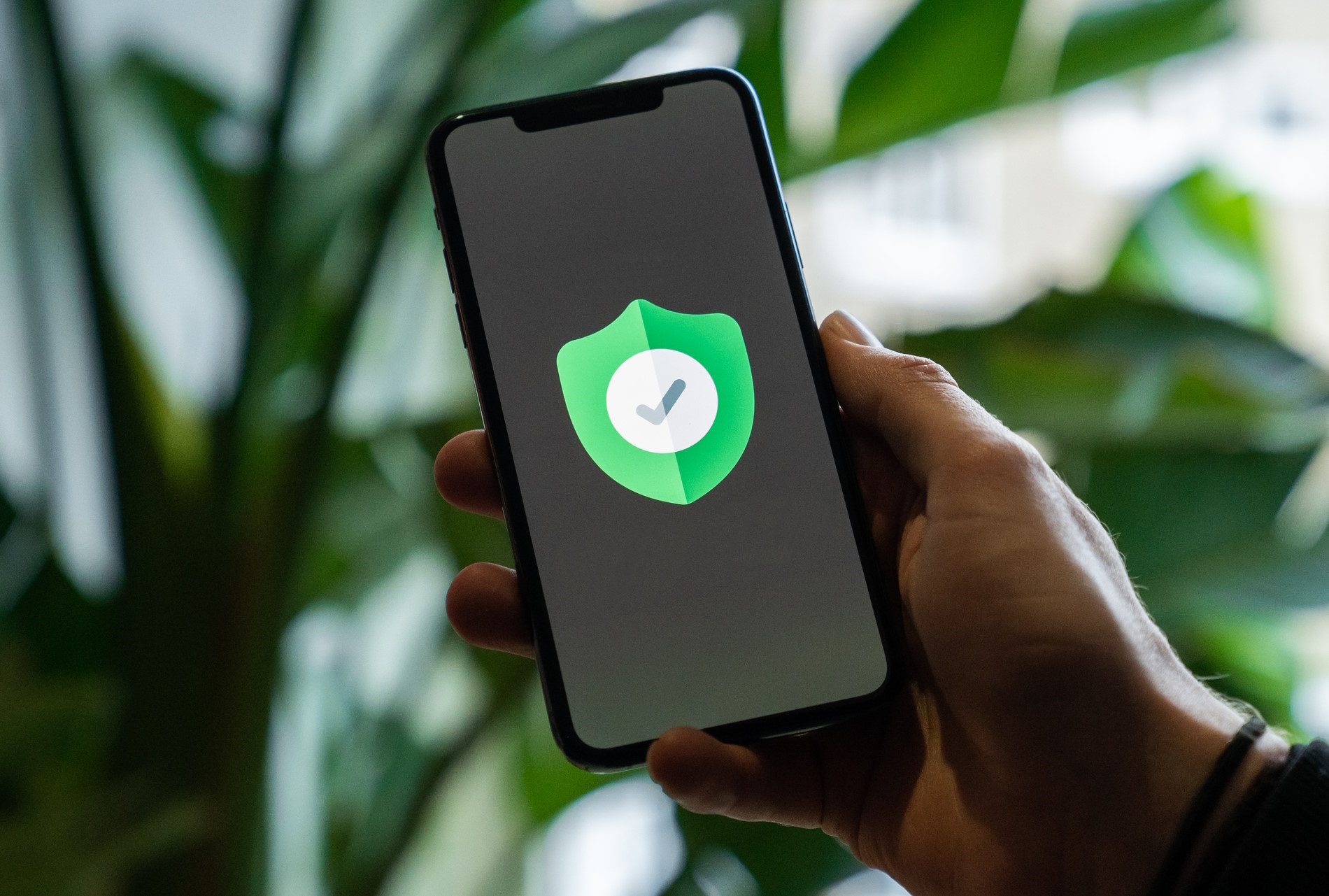 Persona con un cellulare in mano e un simbolo di scudo verde